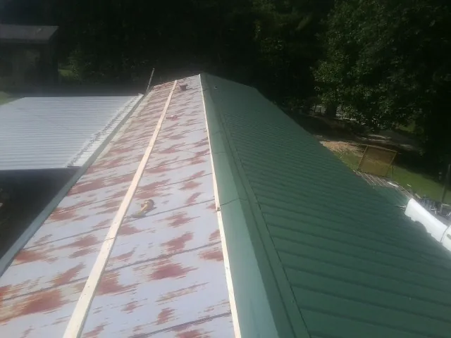 Old rusted panels beside newly installed green metal roofing — Wind Damage Roof Repair by Roofing Brothers in Barnhart