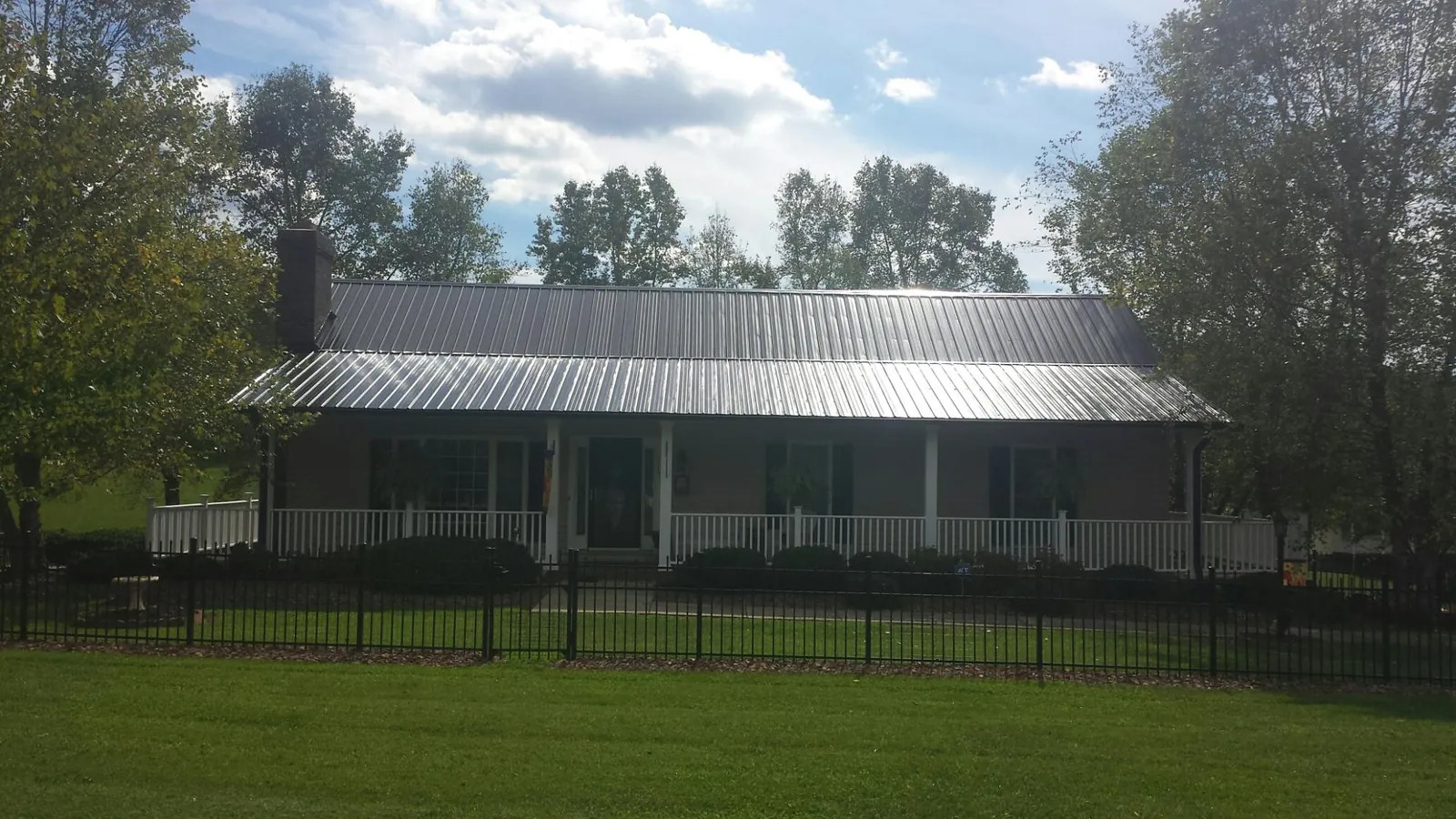 Gray metal roof on a brick ranch with a full width front porch — Gutter Guard Installation work by our crew in Barnhart