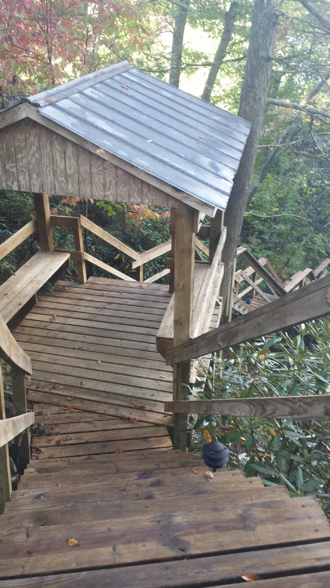 Metal roofed shelter over wooden steps on a wooded walkway — Skylight Repair & Installation work by our crew in Barnhart