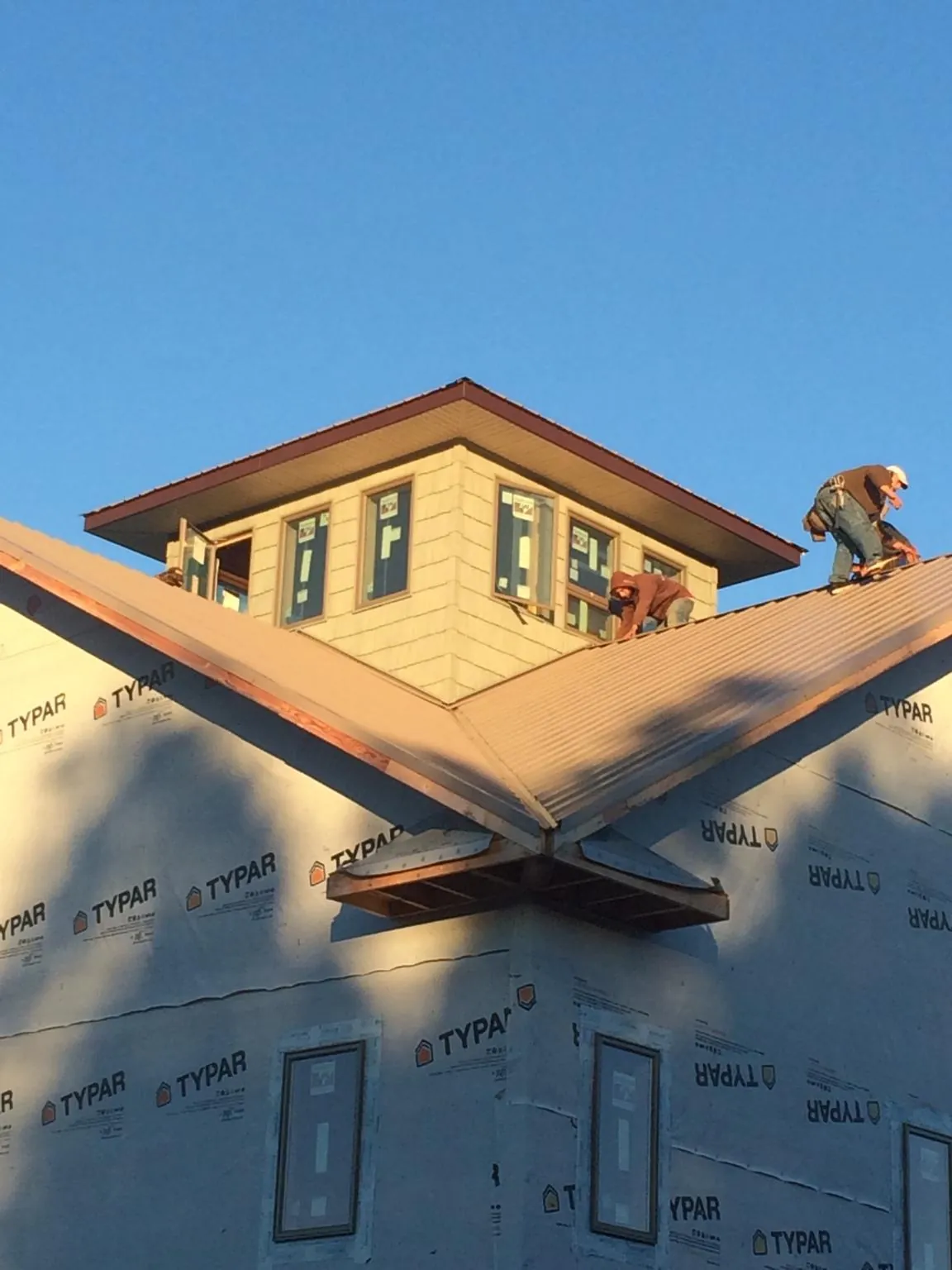 Roofers working around a rooftop cupola on a new metal roof at sunset — Roof Waterproofing in Barnhart by Roofing Brothers
